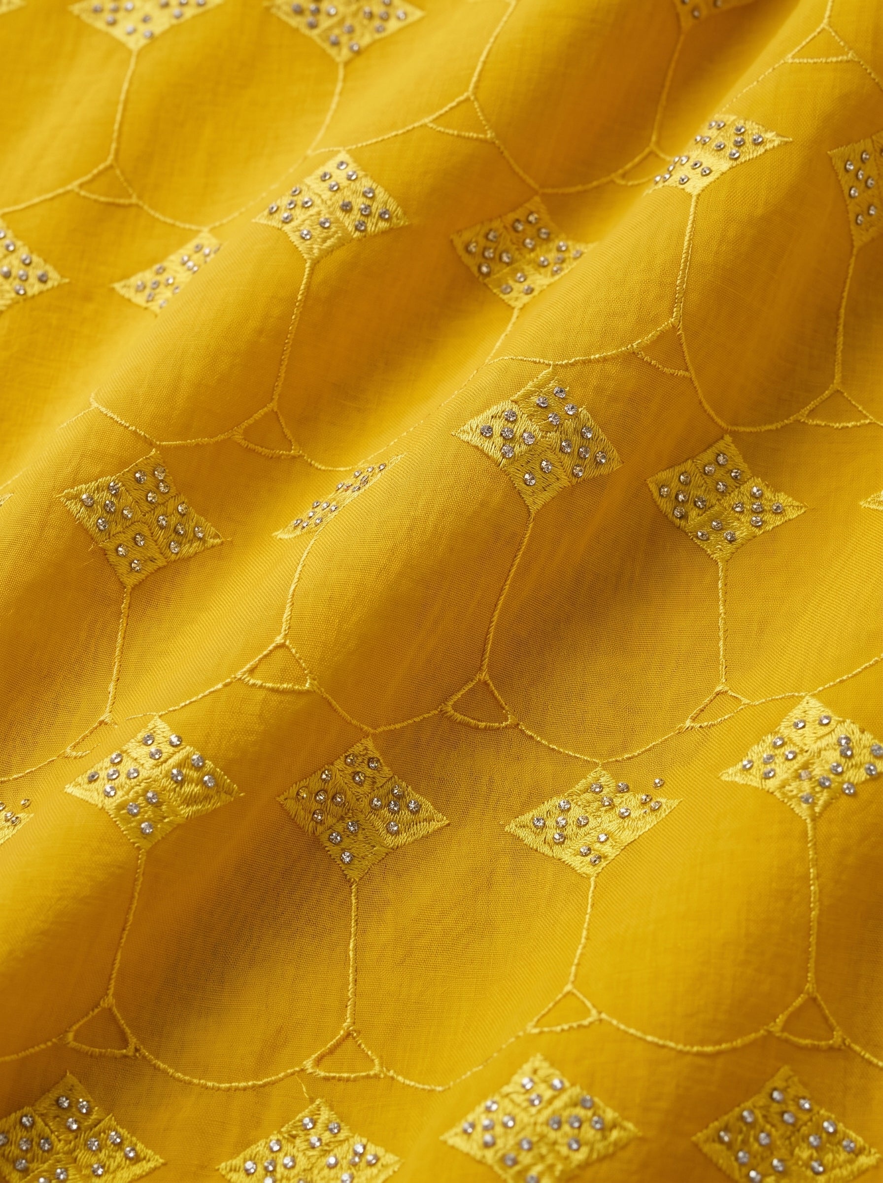 Vibrant mustard yellow Swiss voile featuring a structured diamond lattice pattern and ornate heavy-duty cutwork embroidery