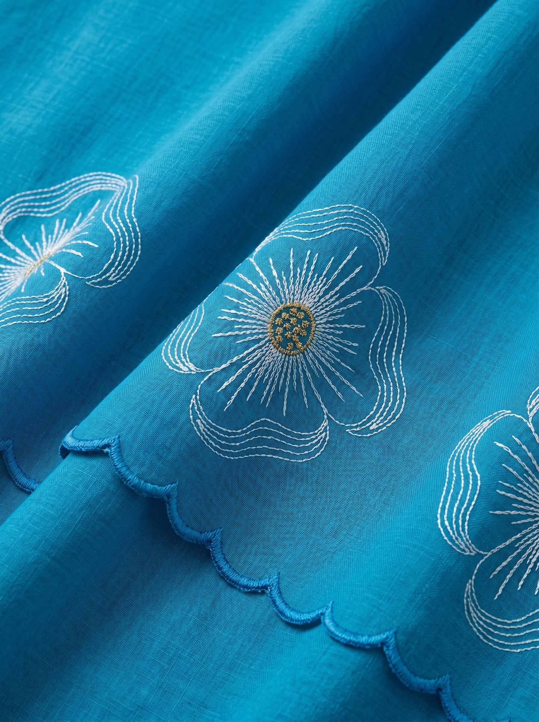 Premium azure blue Swiss voile featuring delicate cutwork floral embroidery and scalloped edges